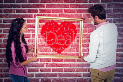 Composite image of smiling couple holding picture frame
