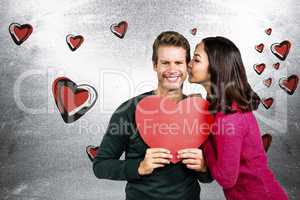 Composite image of woman kissing boyfriend with red heart shape