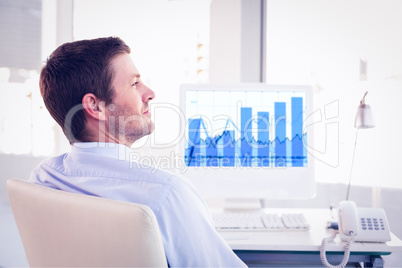 Composite image of smiling businessman sitting at his desk