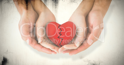 Composite image of couple holding broken heart in hands