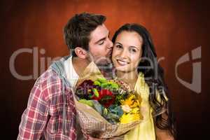 Composite image of smiling woman holding bouquet and being kisse