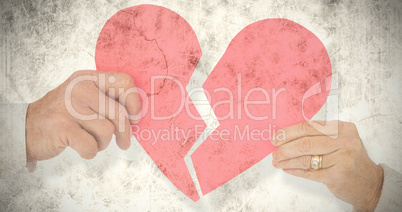 Composite image of couple holding a broken paper heart