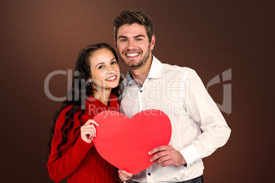 Composite image of happy couple holding paper heart