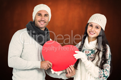 Composite image of smiling couple holding paper heart