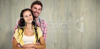 Composite image of happy couple hugging and looking at camera