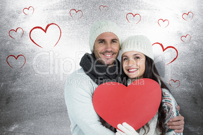 Composite image of smiling couple holding paper heart