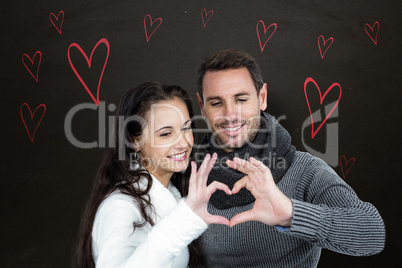 Composite image of smiling couple making heart shape with hands