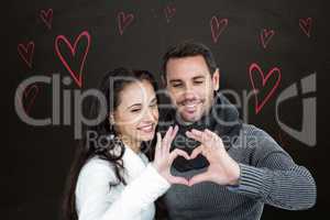Composite image of smiling couple making heart shape with hands