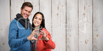 Composite image of portrait of couple making heart shape with ha