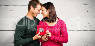 Composite image of happy couple holding gift box