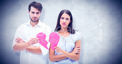 Composite image of upset couple holding two halves of broken hea