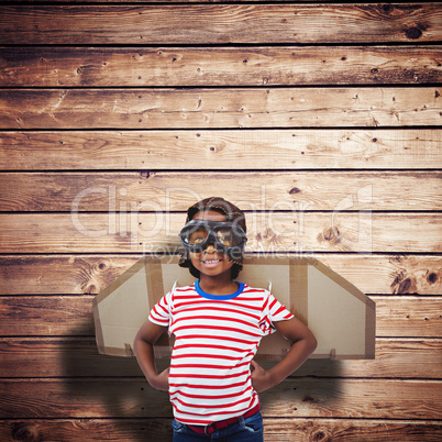 Composite image of smiling boy pretending to be pilot