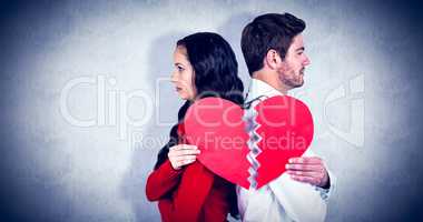 Composite image of couple back to back holding heart halves