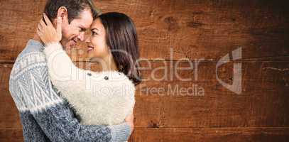 Composite image of cheerful couple in warm clothing embracing ea