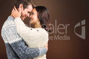 Composite image of cheerful couple in warm clothing embracing ea