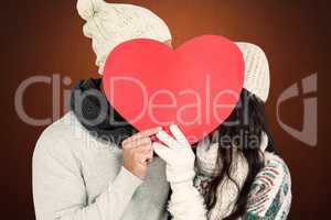 Composite image of smiling couple holding paper heart