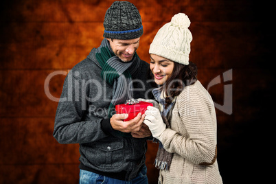 Composite image of festive couple exchanging a gift