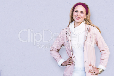 Composite image of smiling woman with hands on hips in front of