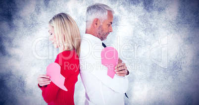 Composite image of couple holding two halves of broken heart