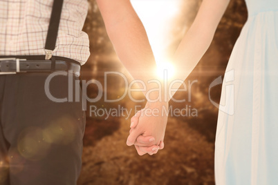 Composite image of hipster couple standing hand in hand