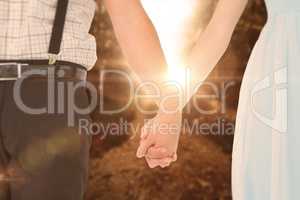Composite image of hipster couple standing hand in hand