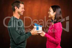 Composite image of smiling couple holding gift box