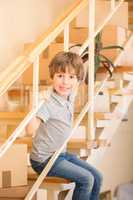 Little boy sitting on stairs indoors