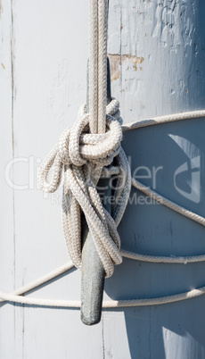 Rope tied on cleat casting shadow on white mast