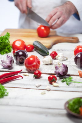 Chef cutting a red tomato his kitchen