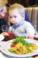 child drinks tomato juice and eats vegetarian dish