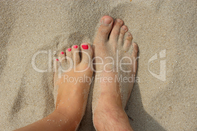 feet of father and his teen daughter on the sand