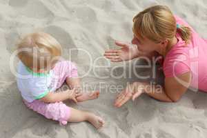 happy mother play about with her baby on the sand