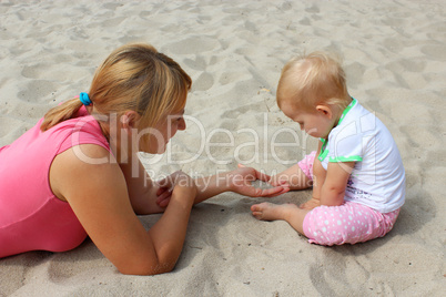 happy mother play about with her baby on the sand