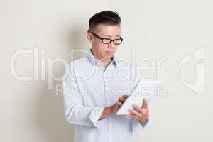 Portrait of mature Asian man using tablet pc