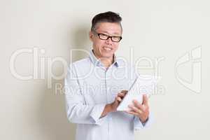 Mature Asian man using tablet pc
