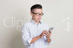 Portrait of mature Asian man using smartphone