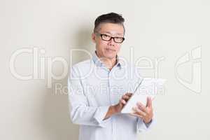 Portrait of mature Asian man using tablet computer