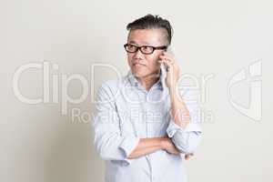 Mature Asian man talking on smartphone