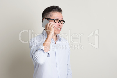 Mature Asian man making call on smartphone