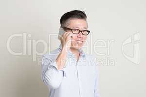 Mature Asian man making call on smart phone