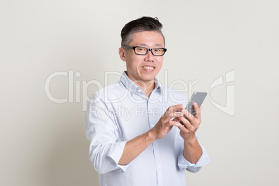 Portrait of mature Asian man using smart phone