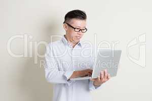 Mature Asian man using laptop pc