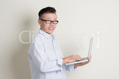 Mature Asian man using pc notebook