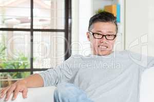 Mature Asian man sitting at home.