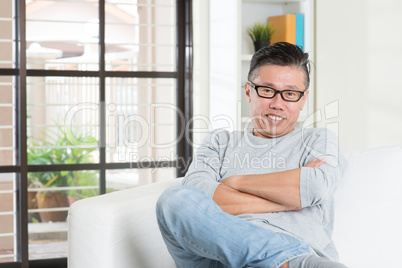 Mature 50s Asian male sitting at home.