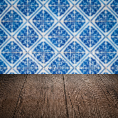 Wood table top and blur vintage ceramic tile pattern wall