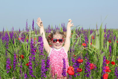 happy little girl standing in colorful meadow