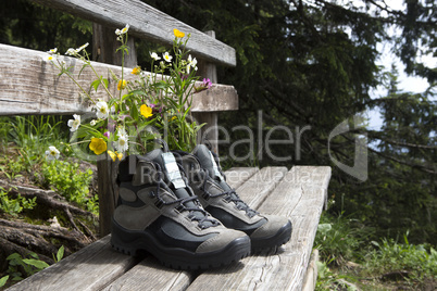 Hiking shoes with flowers on a bench