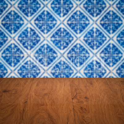 Wood table top and blur vintage ceramic tile pattern wall