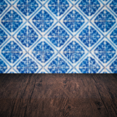 Wood table top and blur vintage ceramic tile pattern wall